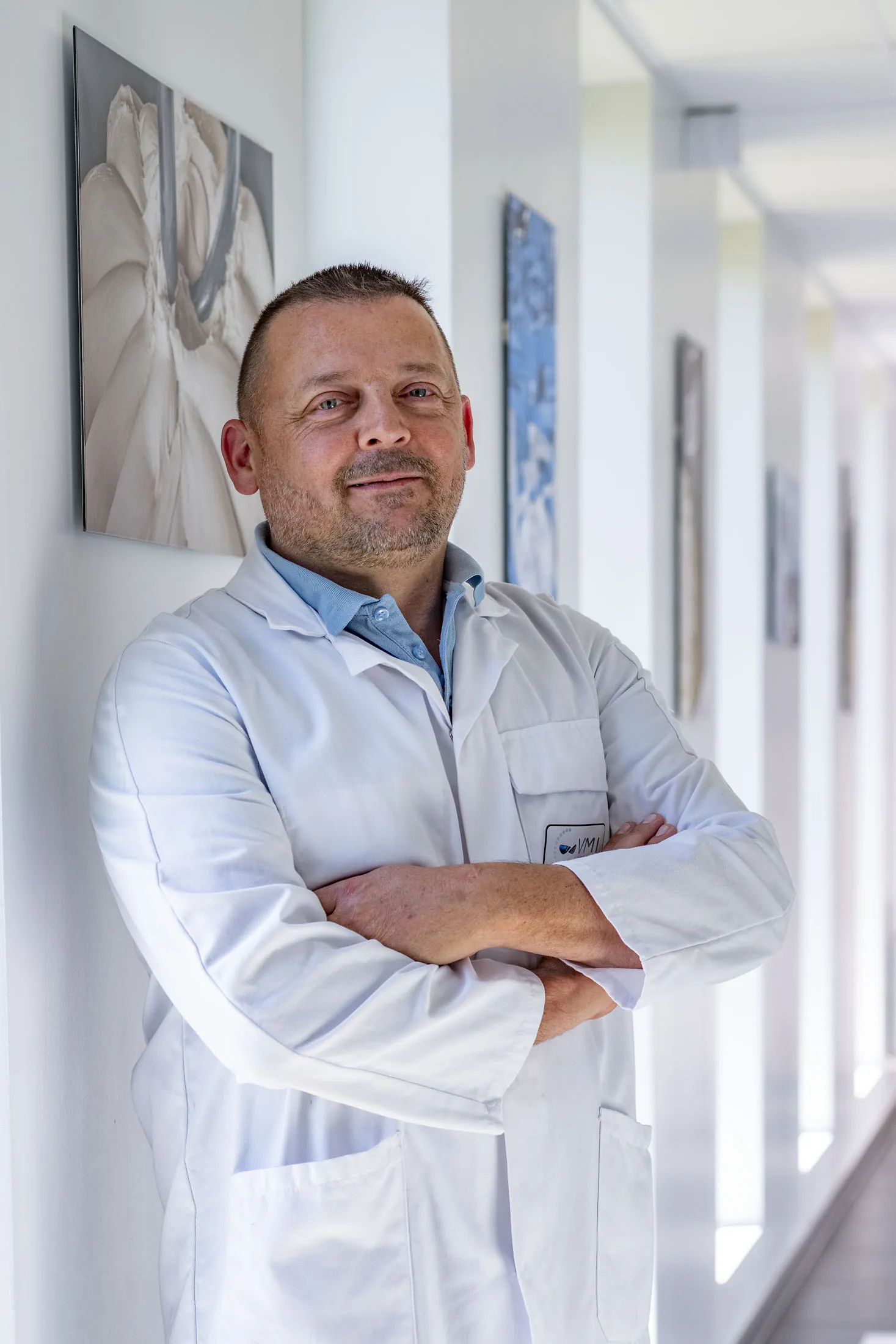 Portrait couleur d'un homme de laboratoire en blouse blanche dans un couloir, Société VMI